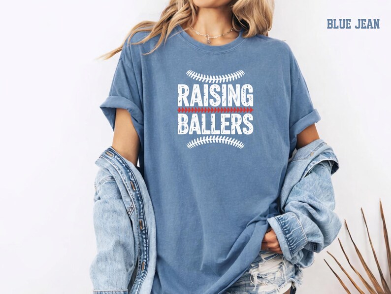 Life at the ball field means raising future athletes. This Raising Ballers Comfort Colors® shirt celebrates the busy but rewarding life of a sports mom. The vintage baseball design and comfortable relaxed fit make it perfect for game day outfits, team events, and casual everyday wear. A great gift for baseball moms and softball moms.