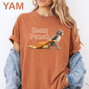 A woman wearing a red t-shirt with a graphic of a monkey and the text "Team Punch" printed on it.