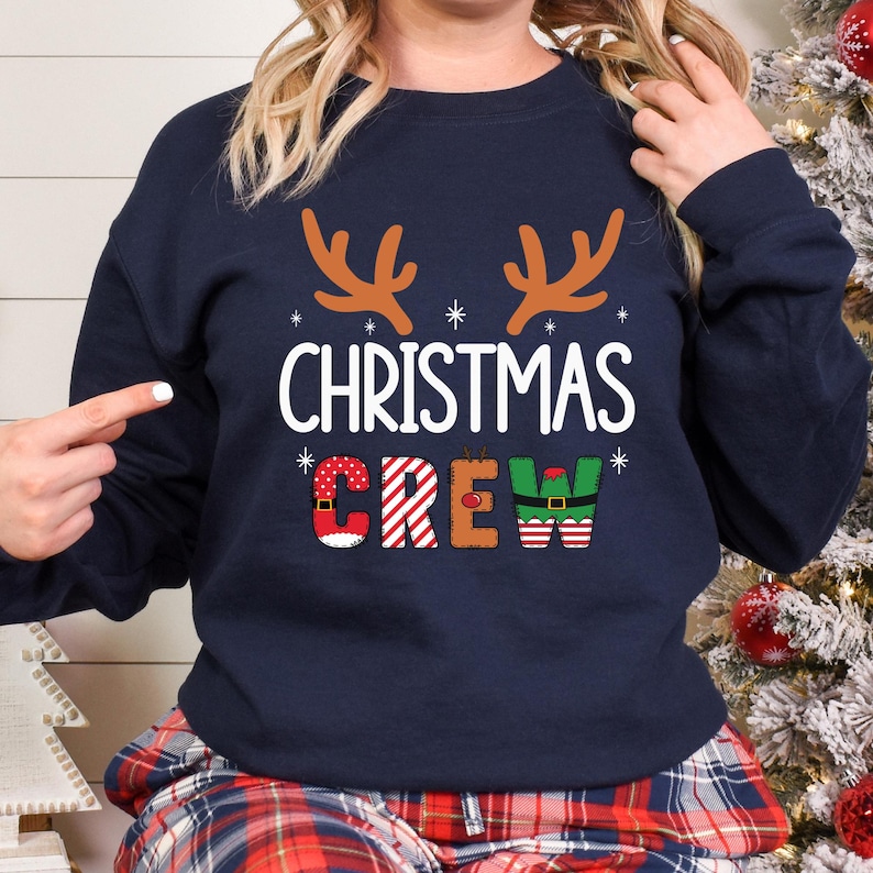 cute christmas crew sweatshirt with reindeer antlers and personalized sleeve name option, matching holiday family sweater for kids and adults, custom christmas shirt for winter celebrations, cozy xmas crew top with festive lettering, personalized holiday gift sweatshirt, christmas pajamas top for family photos, fun reindeer themed christmas sweater, holiday party outfit idea, custom name christmas crew shirt, adorable winter sweatshirt for holiday season