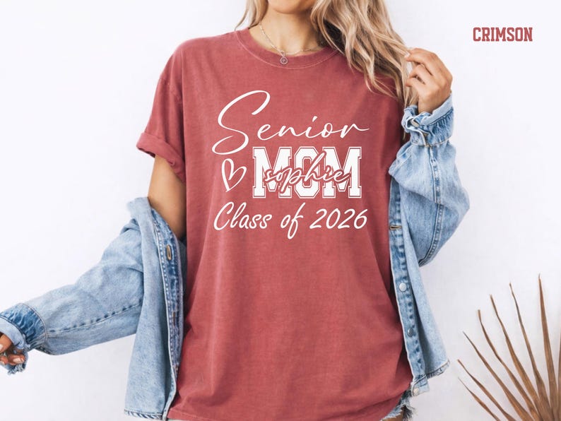 Comfort Colors® Class of 2026 mom shirt with a soft vintage blue jean look and clean white print. The design highlights Senior, MOM, custom name text and Class of 2026 wording for a proud graduation mom style. Great for senior night, graduation day, family photos, school spirit outfits and personalized gifts for moms of graduates.