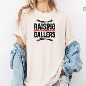 Celebrate baseball season in style with this Raising Ballers Comfort Colors® shirt. Designed for baseball moms and softball moms, this comfortable vintage tee is ideal for cheering from the stands, attending tournaments, and supporting your young athletes. A thoughtful gift for proud sports moms.