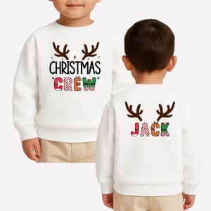 cute christmas crew sweatshirt with reindeer antlers and personalized sleeve name option, matching holiday family sweater for kids and adults, custom christmas shirt for winter celebrations, cozy xmas crew top with festive lettering, personalized holiday gift sweatshirt, christmas pajamas top for family photos, fun reindeer themed christmas sweater, holiday party outfit idea, custom name christmas crew shirt, adorable winter sweatshirt for holiday season