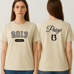A woman wearing a 2013 limited edition t-shirt with the name " Paige" and the number "13" printed on the back.