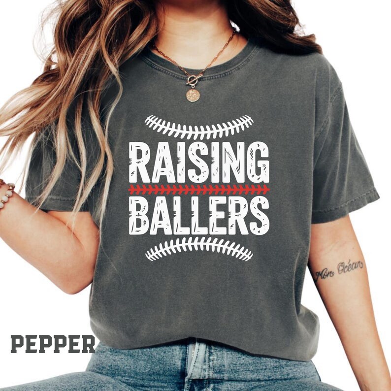 If your weekends are filled with baseball games and softball practices, this Raising Ballers Comfort Colors® shirt is made for you. The stylish sports graphic and vintage garment dyed look create a comfortable and trendy game day outfit. Perfect for cheering in the stands and supporting your favorite player.