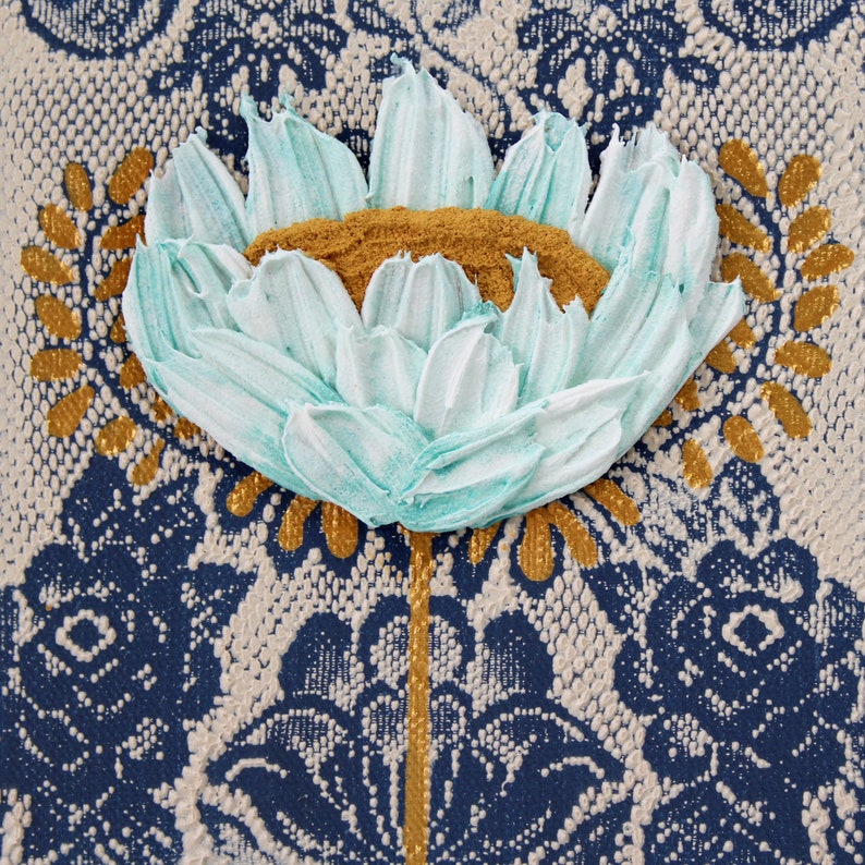 Center view of miniature painting in art deco style with a blue impasto flower on a textured background with golden leaves