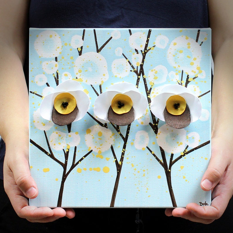 Held in hand for scale view of cheerful painting gift for mom with 3d flowers on a small canvas art in blue, yellow, and white