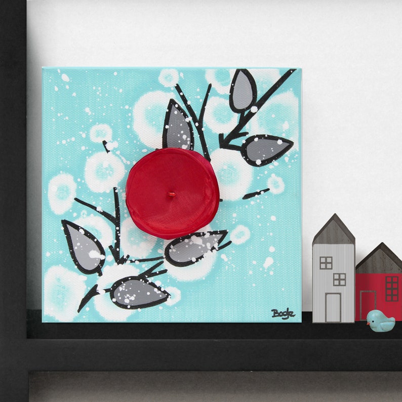 Shelf decor setting view of painting on mini canvas with 3d flower in red, black, and aqua