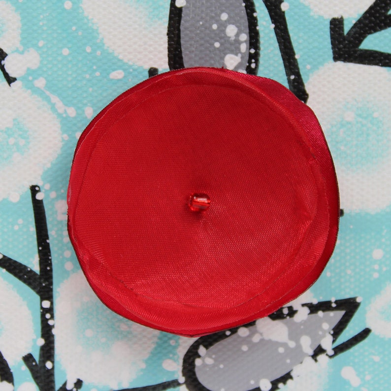 Close up of hand crafted flower on painting on mini canvas with 3d flower in red, black, and aqua
