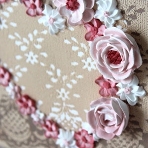 Angled close up view of little valentine heart painting with sculpted roses on a lacy textured canvas for gift for women