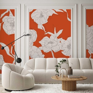 May include: A living room interior design featuring a white sofa and a white armchair with a modern design. The wall behind the furniture is covered with a wallpaper featuring a large-scale floral pattern in white on a bright orange background.