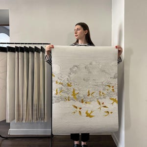 May include: A roll of wallpaper featuring a flock of yellow birds in flight against a cloudy sky. The wallpaper has a textured, off-white background and a detailed illustration of the birds.