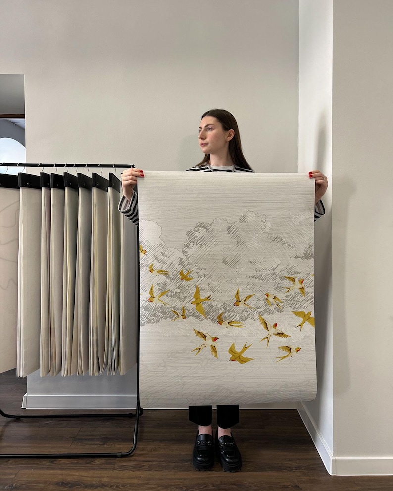 May include: A roll of wallpaper featuring a flock of yellow birds in flight against a cloudy sky. The wallpaper has a textured, off-white background and a detailed illustration of the birds.