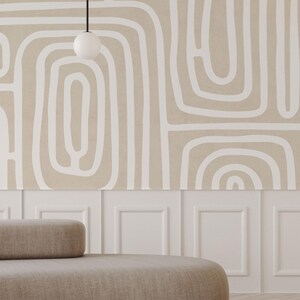 May include: A neutral-toned room featuring a beige sofa with a rounded back and a white wall with a decorative pattern. The wall has a beige background with white abstract lines. A white globe light hangs from the ceiling.
