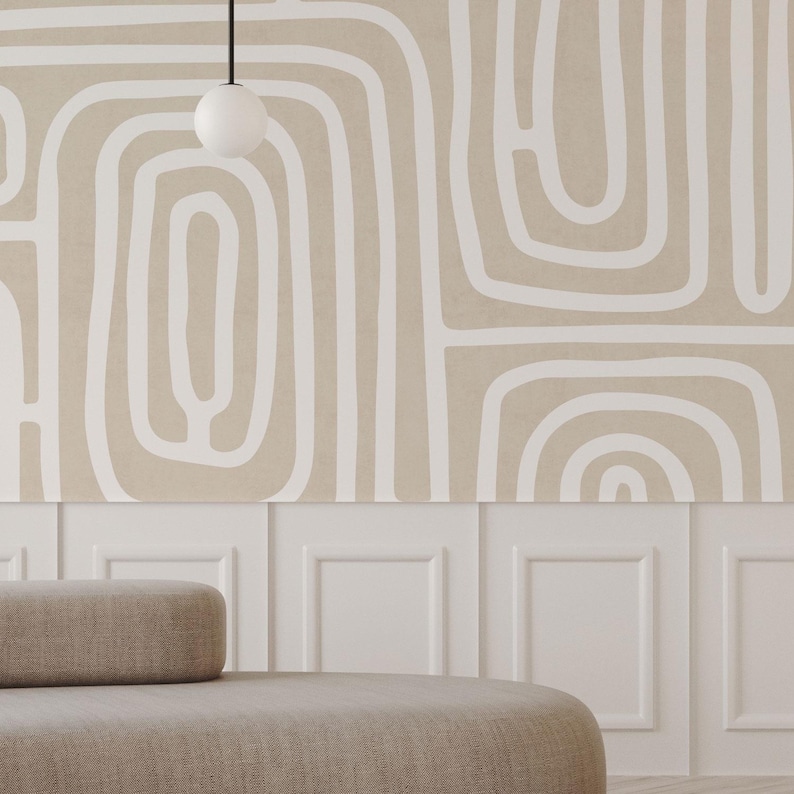 May include: A neutral-toned room featuring a beige sofa with a rounded back and a white wall with a decorative pattern. The wall has a beige background with white abstract lines. A white globe light hangs from the ceiling.