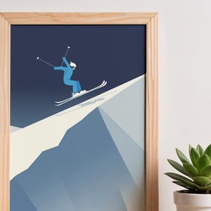 May include: A framed print featuring a skier in a blue outfit, skiing down a snow-covered mountain. The artwork has a minimalist style with a dark blue sky background and a light wood frame. A succulent plant in a white pot is in the foreground.