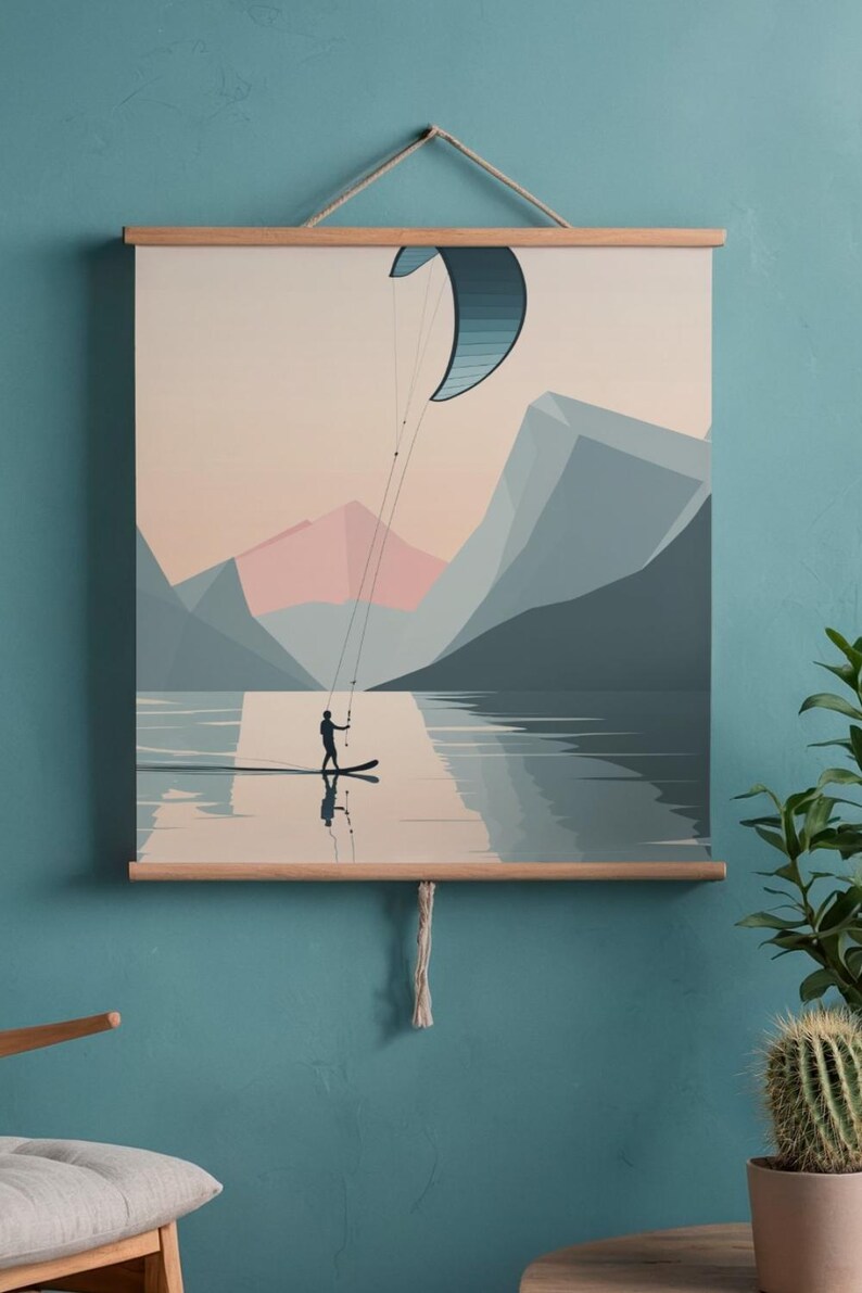 May include: A wall art print depicting a watersports scene. A person is kitesurfing on a lake, with mountains in the background. The print is framed with wooden bars and a hanging string. The color palette includes blues, pinks, and beige.