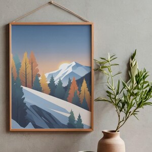 May include: A framed landscape art print depicting a mountain scene with snow-covered slopes, evergreen and autumn-colored trees, and a setting sun. The artwork is displayed on a gray wall, with a vase of greenery and two ceramic pots in the foreground.