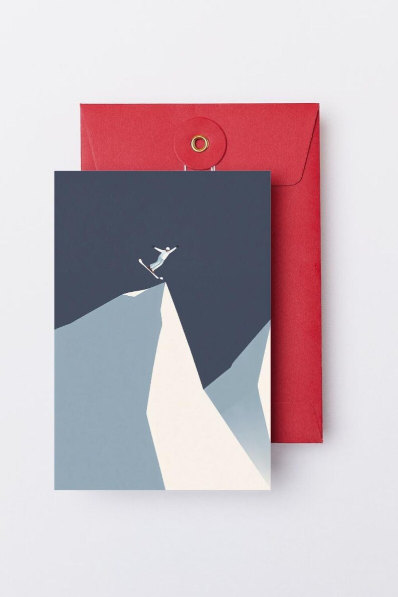 May include: Greeting card with a skier jumping off a mountain peak, set against a dark blue sky. The card is paired with a red envelope. The illustration uses shades of blue, white, and gray.