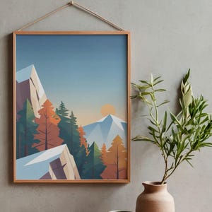 May include: A framed art print featuring a stylized mountain landscape with snow-capped peaks, evergreen and autumn-colored trees, and a setting sun. The artwork is in a wooden frame and hangs on a gray wall. A vase with greenery sits below.