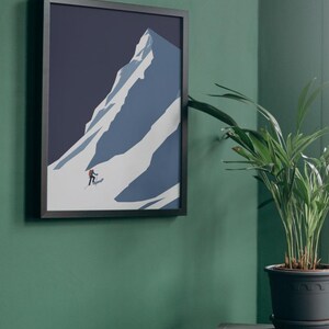 May include: Framed art print featuring a minimalist illustration of a snow-covered mountain with a skier. The artwork is in shades of blue and white, set against a dark blue sky. The print is in a black frame.