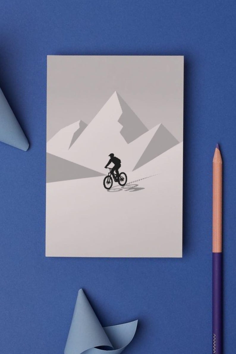 May include: A grayscale illustration of a mountain biker on a mountain trail. The cyclist is a black silhouette against a light gray background with geometric mountain shapes. A blue background with a pencil and paper accents the image.