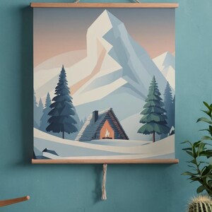 May include: A framed wall art print showing a winter mountain scene. The artwork features a snow-covered landscape with a cabin, evergreen trees, and a large mountain in the background. The print is mounted on wooden bars and suspended by a string.