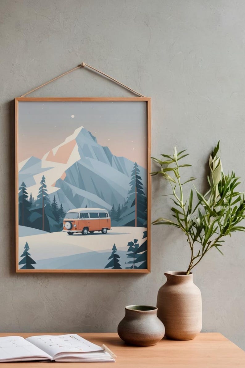 May include: A framed print featuring a stylized mountain landscape with an orange camper van. The artwork has a minimalist aesthetic with a color palette of blues, oranges, and whites. The print is hung by a natural rope.