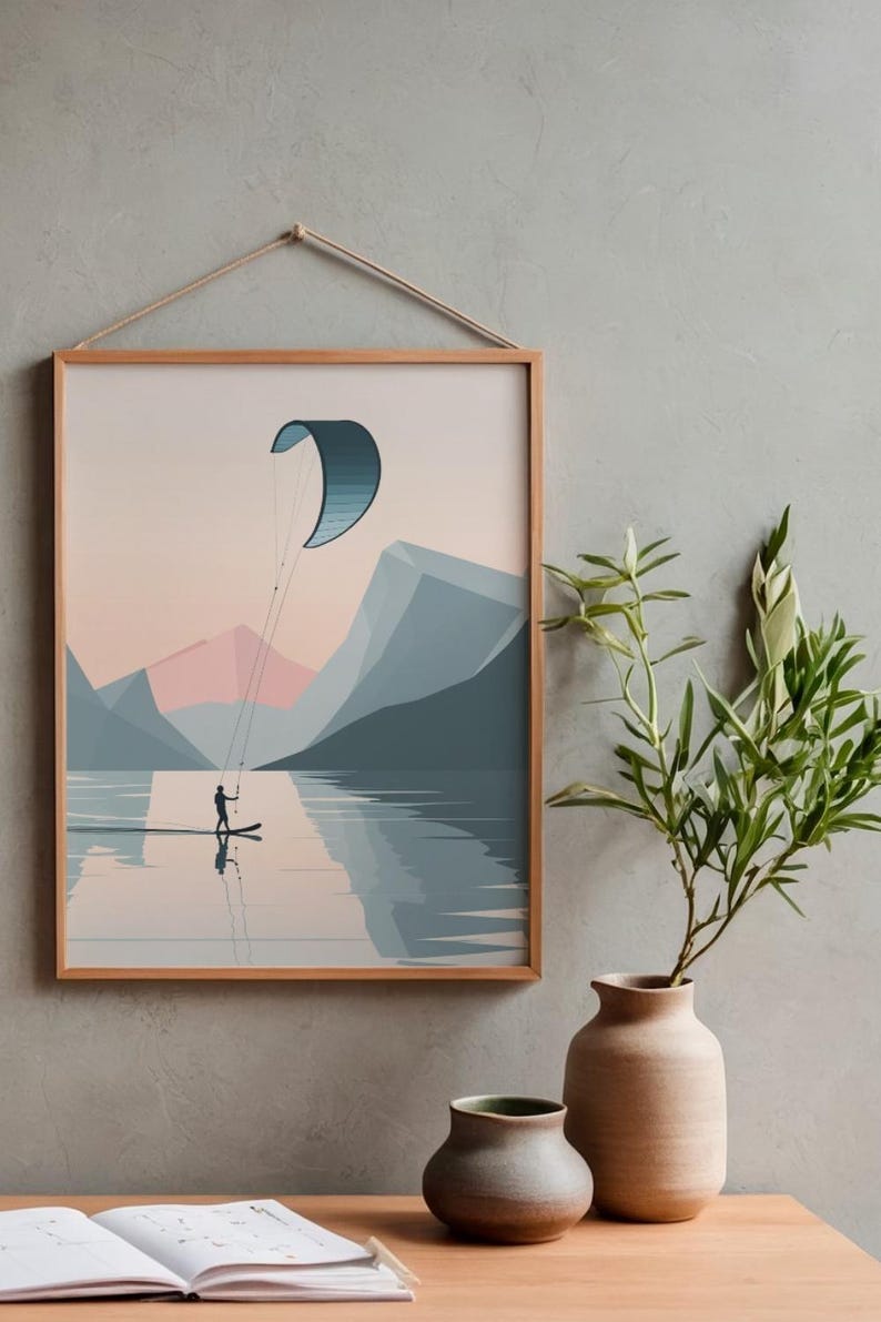 May include: A framed art print depicts a watersports scene. A person on a paddleboard is kiteboarding on a lake, with mountains in the background. The artwork is in a minimalist style, with a color palette of blues, pinks, and beige.