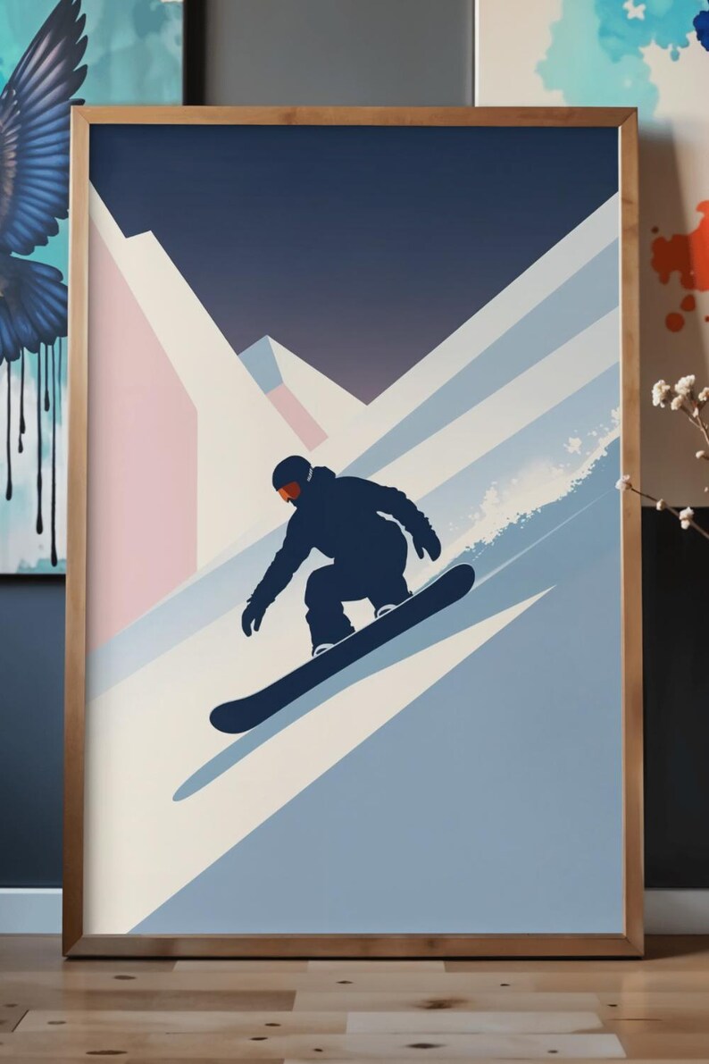 May include: A framed art print featuring a snowboarder in silhouette, carving down a snowy mountain slope. The artwork uses a palette of navy, light blue, pink, and white, with a gradient sky. The snowboarder is wearing a dark blue outfit and orange goggles.