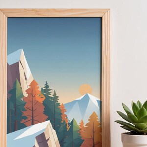 May include: A framed art print featuring a stylized mountain landscape. The artwork depicts snow-capped mountains, evergreen and autumn-colored trees, and a setting sun against a blue sky. The frame is made of light-colored wood.