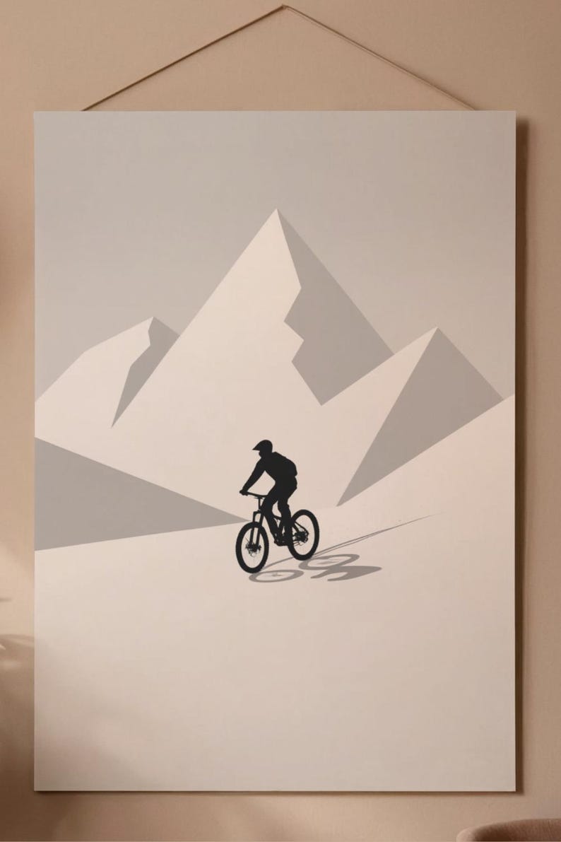 May include: A minimalist art print featuring a black silhouette of a mountain biker descending a slope. The artwork showcases a rider on a bicycle against a backdrop of stylized, light gray mountain peaks. The print is mounted and ready to hang.