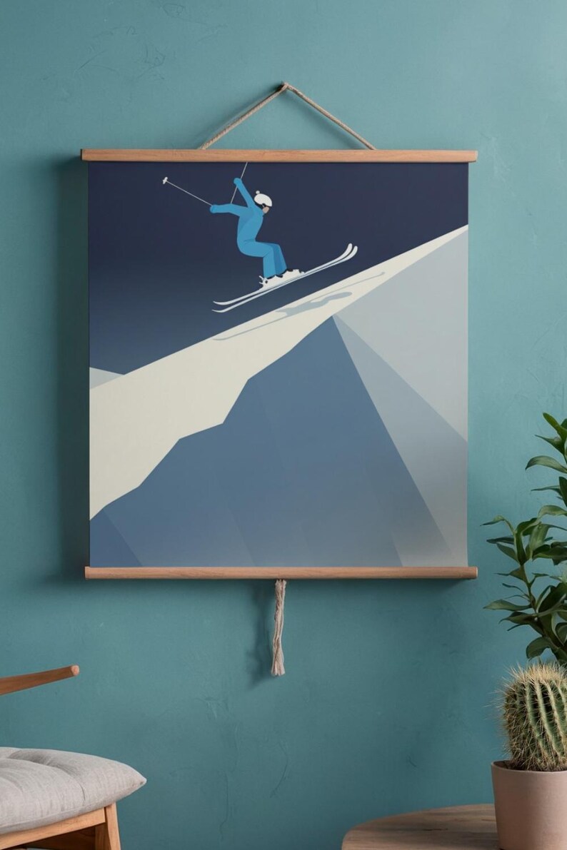 May include: A framed print featuring a skier in a blue jumpsuit and white helmet, mid-air on a snowy mountain slope. The artwork uses a minimalist style with shades of blue and white, mounted on wooden bars.