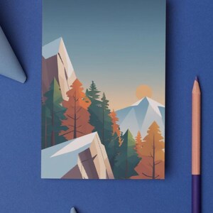 May include: A rectangular art print featuring a mountain landscape with trees and a setting sun. The artwork uses a geometric style with shades of blue, orange, and green. A purple pencil and blue paper are on a blue surface.