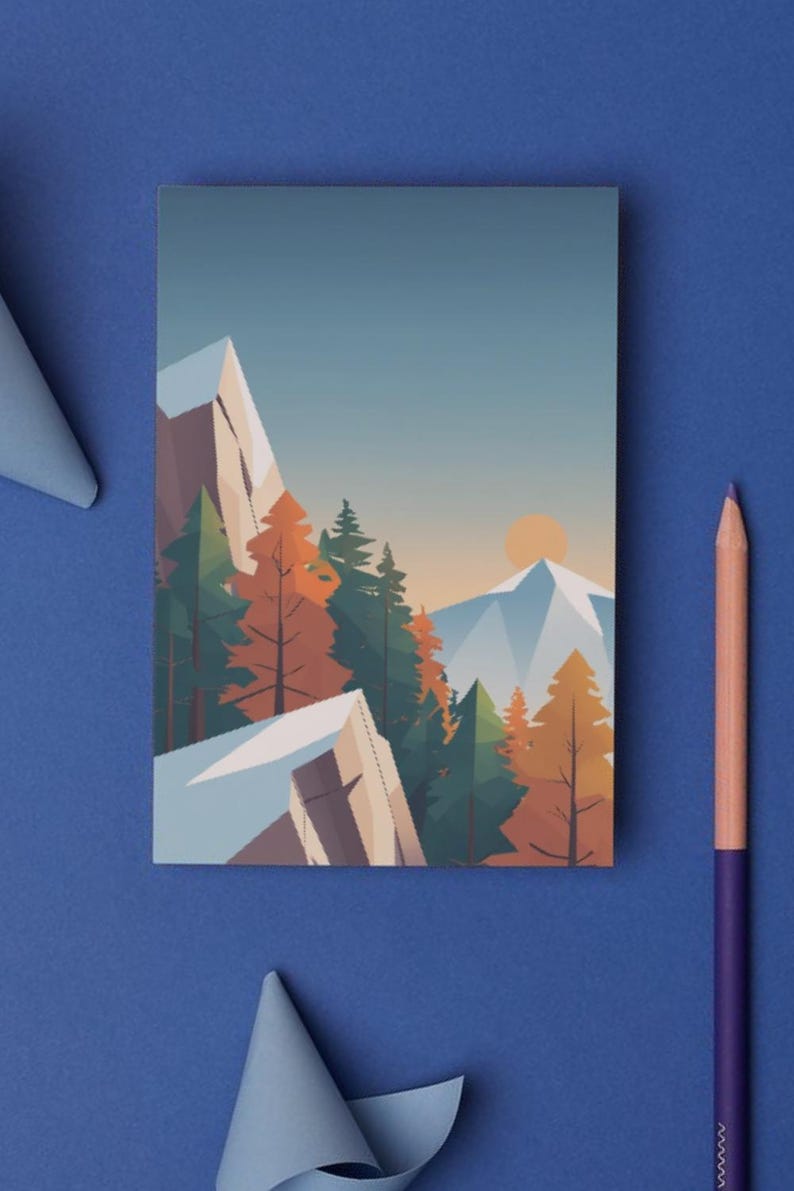 May include: A rectangular art print featuring a mountain landscape with trees and a setting sun. The artwork uses a geometric style with shades of blue, orange, and green. A purple pencil and blue paper are on a blue surface.