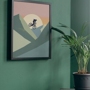 May include: Framed wall art featuring a silhouette of a mountain biker against a sunset backdrop. The artwork uses a palette of muted greens, blues, and oranges. The black frame complements the artwork, creating a modern aesthetic. Perfect for home decor.