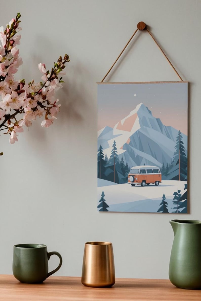May include: A wall art print depicting a winter landscape with a mountain, pine trees, and an orange van. The artwork is displayed on a wooden frame and hung by a brown string. A green mug, a gold vase, and a green pitcher are in the foreground.