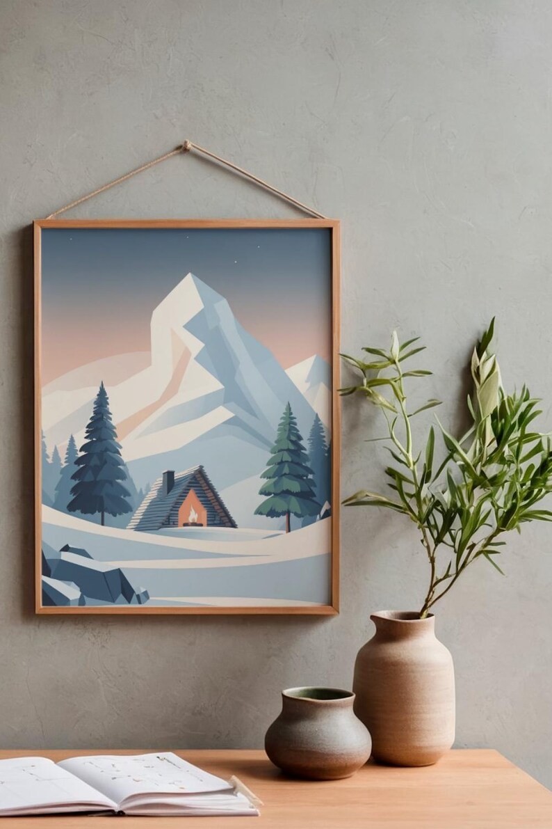May include: A framed print of a winter scene, showing a cabin, snow, and mountains. The artwork features a cabin with a lit fireplace, evergreen trees, and a large mountain in the background. The frame is made of light-coloured wood.