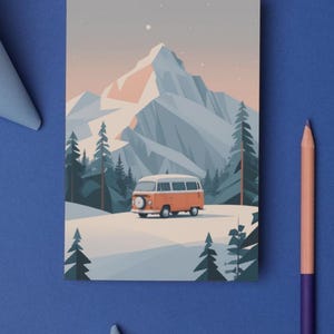 May include: An illustration of an orange and white camper van driving through a snowy landscape with a mountain backdrop. The artwork features a minimalist style with a color palette of orange, white, blue, and gray. The image is on a blue surface with a pencil and paper decorations.