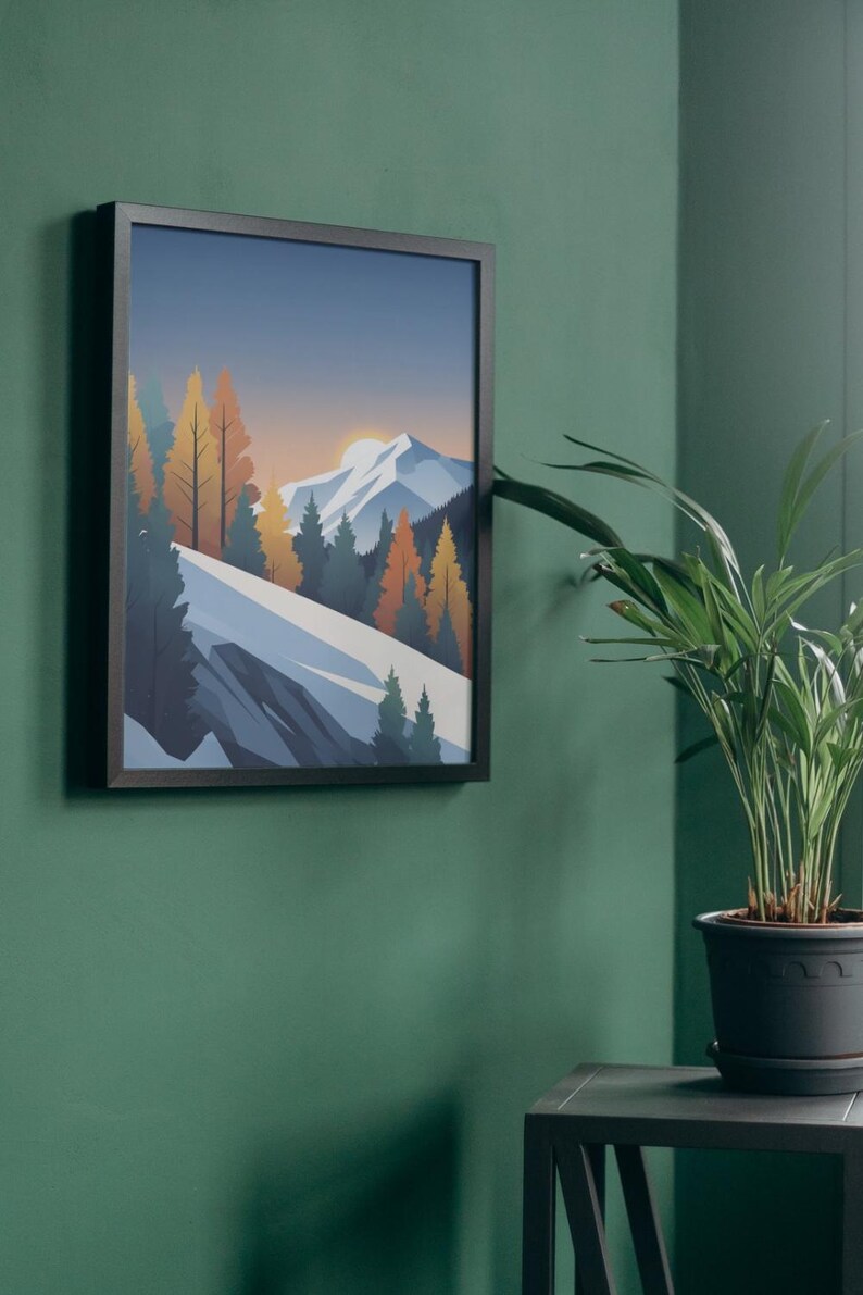 May include: Framed art print featuring a mountain landscape with a sunset. The artwork depicts a snow-covered mountain range, evergreen trees, and colorful autumn trees. The print is in a black frame and hangs on a green wall.