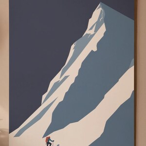 May include: A minimalist art print depicting a mountain climber ascending a snow-covered mountain. The artwork features a color palette of blue, white, and a dark navy background. The climber is wearing a red backpack. The print is mounted on a wooden frame.