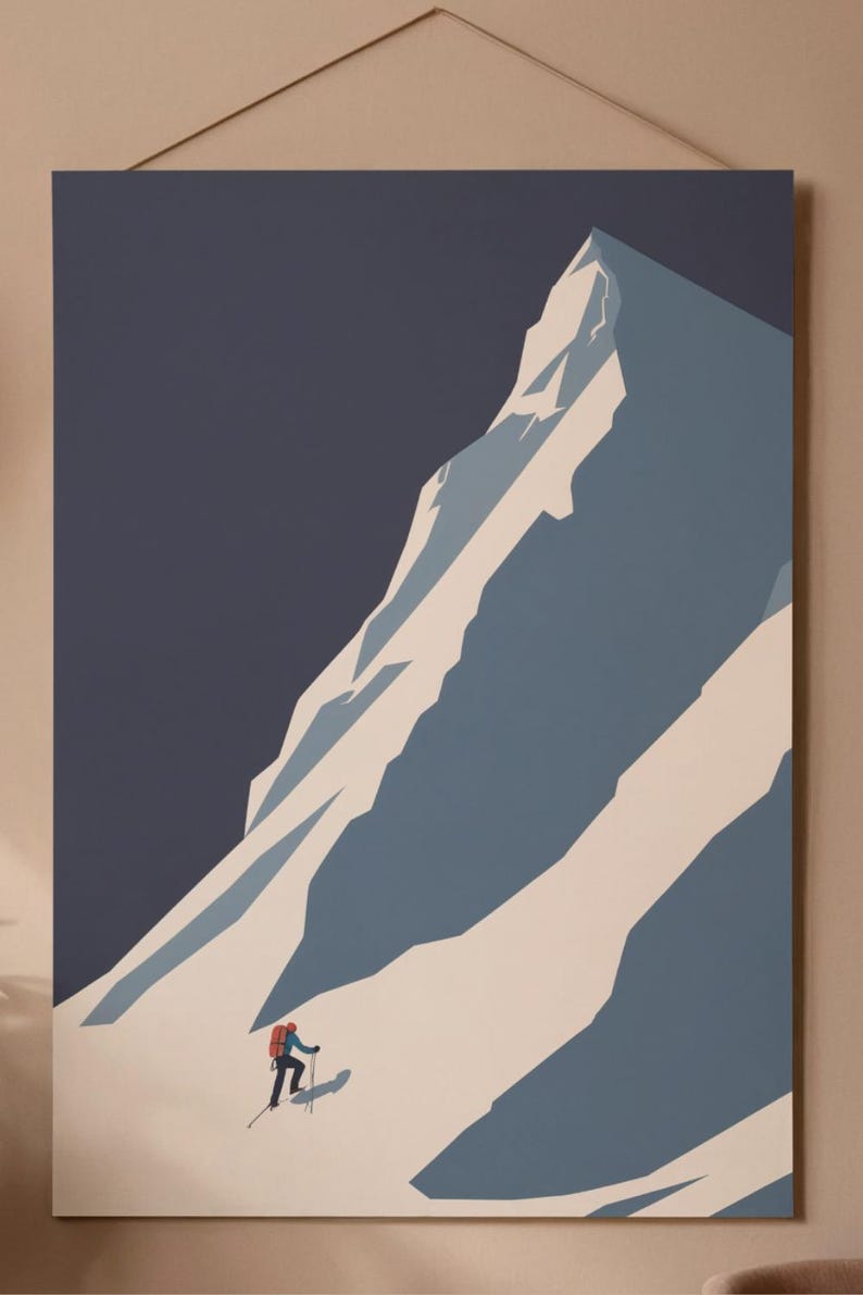 May include: A minimalist art print depicting a mountain climber ascending a snow-covered mountain. The artwork features a color palette of blue, white, and a dark navy background. The climber is wearing a red backpack. The print is mounted on a wooden frame.