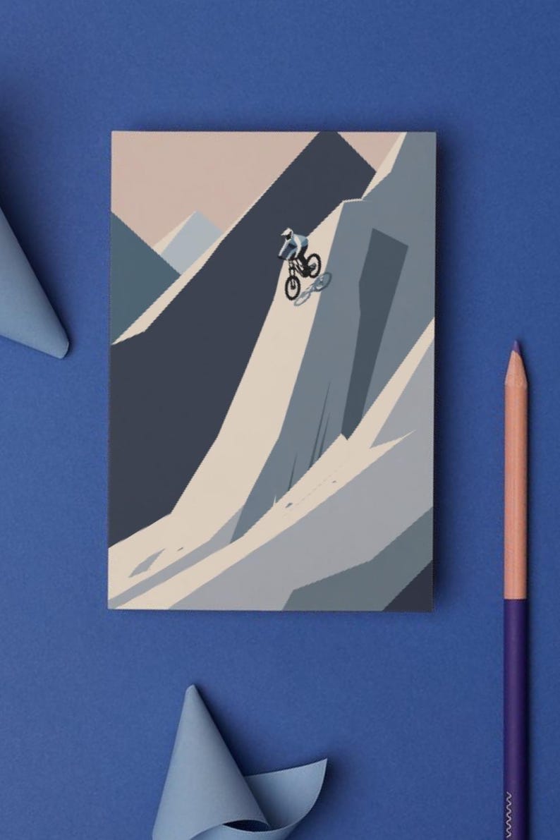 May include: A mountain biking illustration on a rectangular card. The artwork depicts a cyclist descending a steep mountain slope. The color palette includes shades of blue, gray, and beige. A purple and peach colored pencil is on the blue surface.