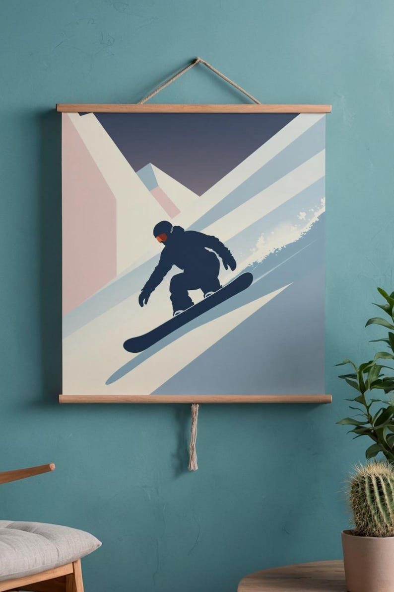 May include: A framed wall art print featuring a snowboarder in a dark blue silhouette, carving down a snowy slope. The background shows a mountain range in shades of blue, white, and pink. The print is held by wooden bars and a rope.