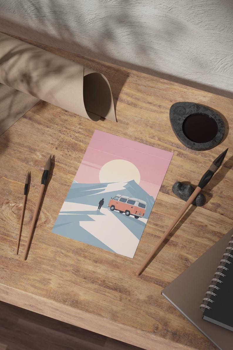 May include: A postcard featuring a retro camper van driving on a snowy mountain road under a large sun. The postcard is on a wooden surface with paint brushes, a notebook, and a stone inkwell.