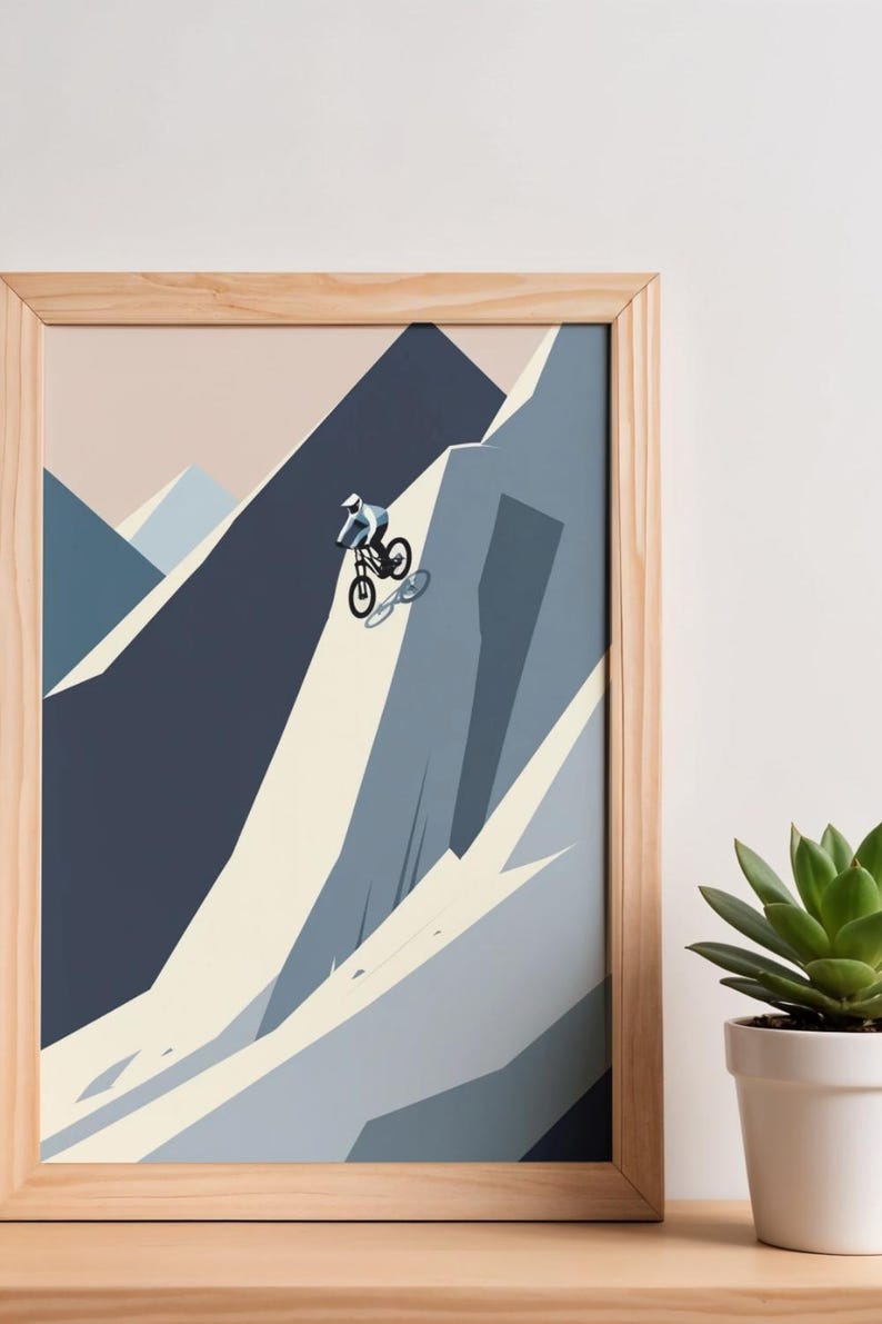 May include: A framed print featuring a mountain biker descending a steep, rocky slope. The artwork uses a minimalist style with shades of blue, gray, and beige. The print is in a natural wood frame, and a succulent plant in a white pot is in the foreground.