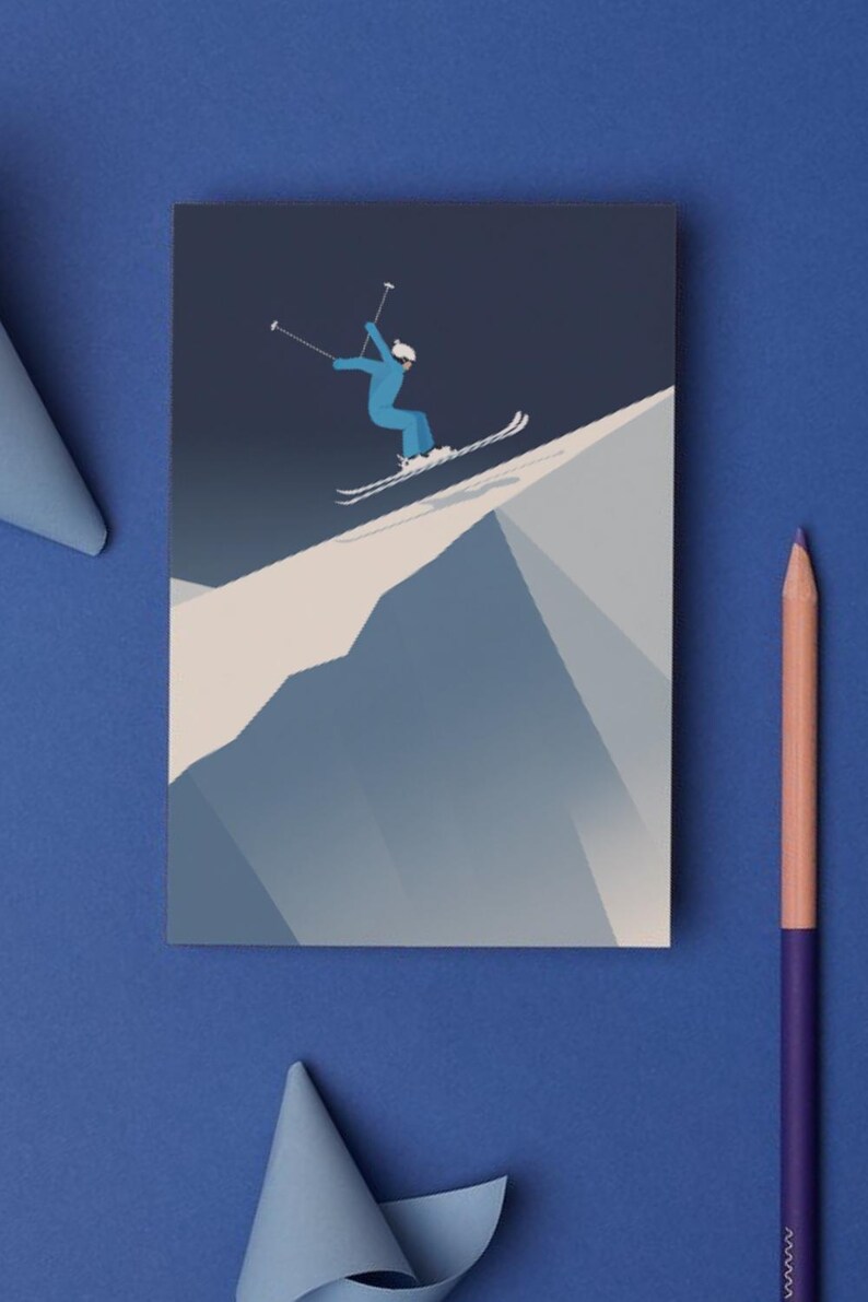 May include: A greeting card featuring a skier in a blue outfit, skiing down a snowy mountain. The illustration is set against a dark blue background. A blue pencil and paper are on the blue surface.