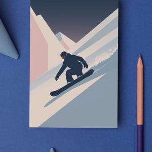 May include: A rectangular card featuring a snowboarder silhouetted against a mountain landscape. The design uses shades of blue, pink, and white. A purple and peach colored pencil is on the blue surface.