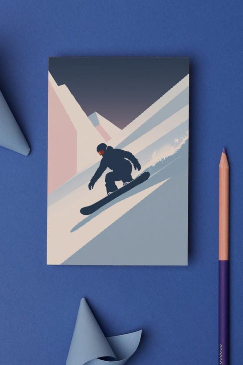 May include: A rectangular card featuring a snowboarder silhouetted against a mountain landscape. The design uses shades of blue, pink, and white. A purple and peach colored pencil is on the blue surface.