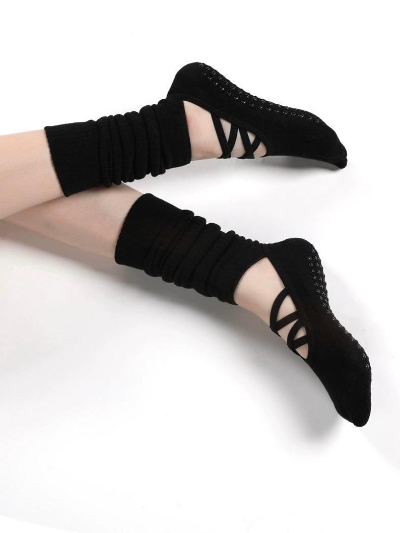 May include: Black yoga socks with crisscross straps and non-slip soles. The socks have a ballet-inspired design and are paired with black leg warmers. The socks and leg warmers are made of a soft, stretchy material.