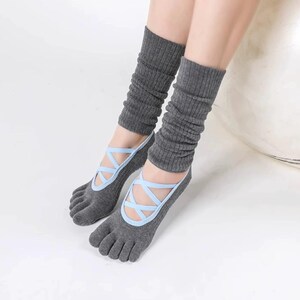 May include: Gray toe socks with light blue crisscross straps, paired with matching gray leg warmers. The socks have individual toe slots and are designed for activities like yoga or dance.